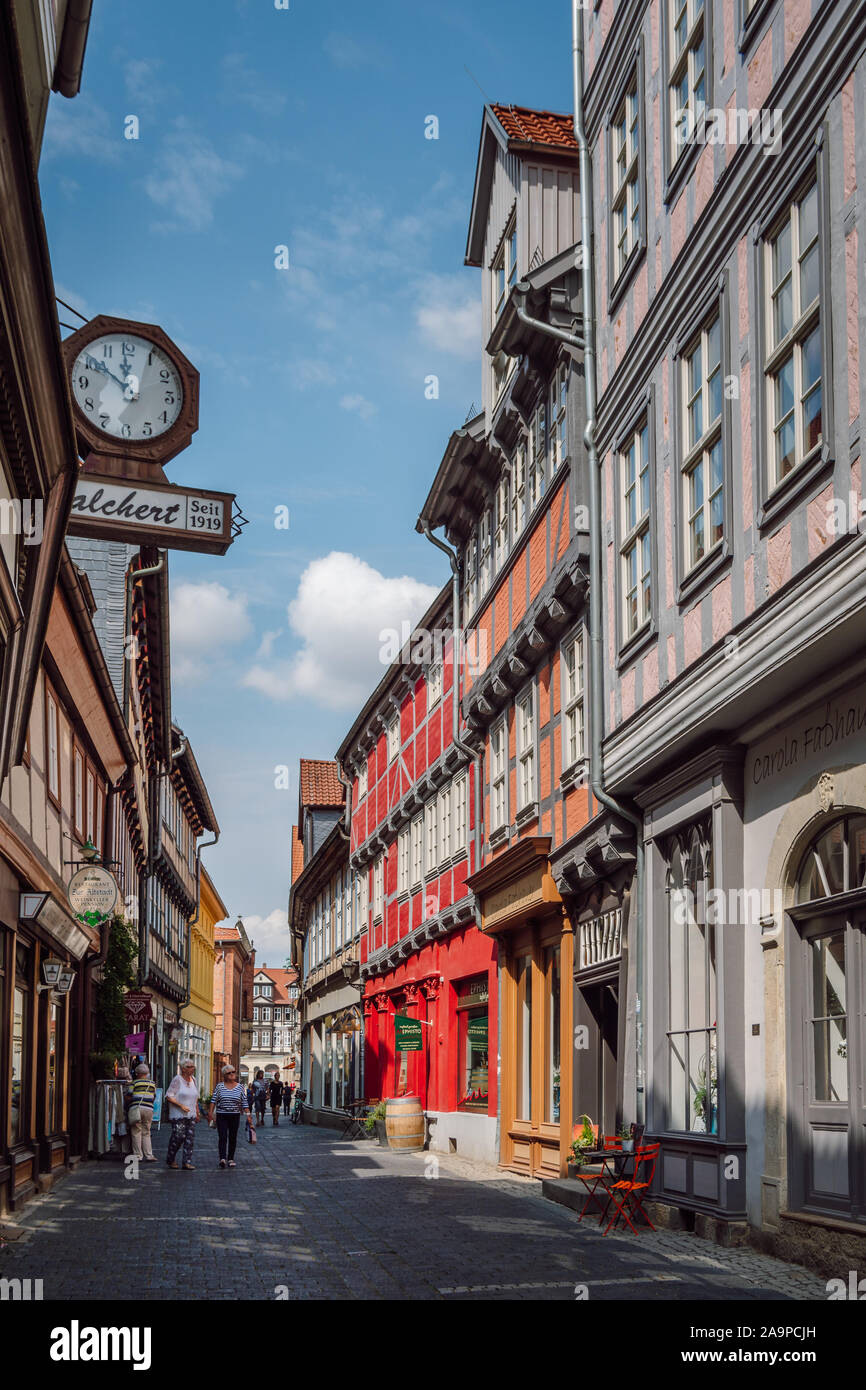 View of a street with colorful half-timbered houses and tourists walking around old town in the UNESCO world heritage city of Quedlinburg. Stock Photo