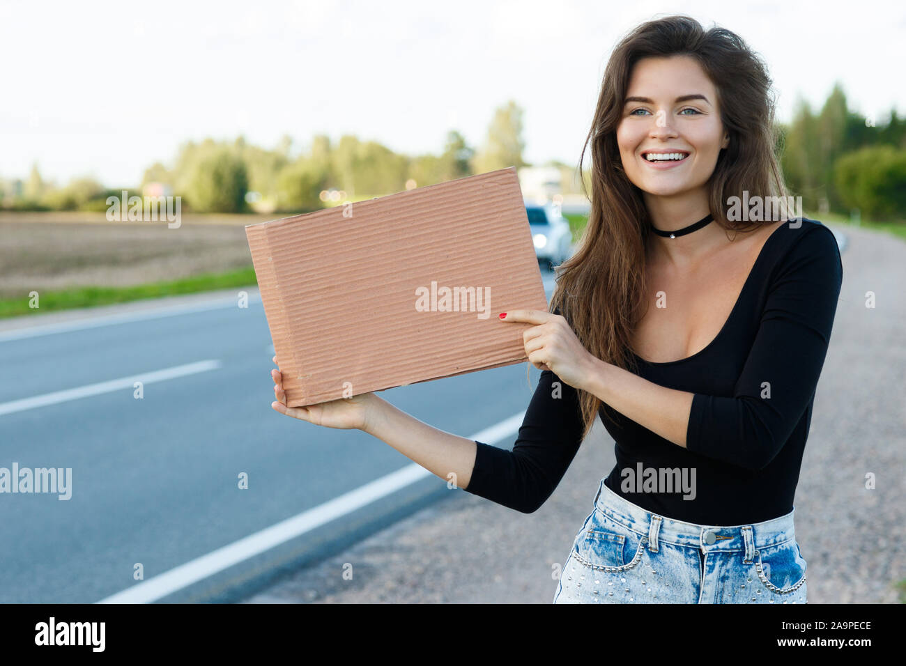 Young woman hitchhiker on the road is holding a blank cardboard sign Stock Photo Alamy