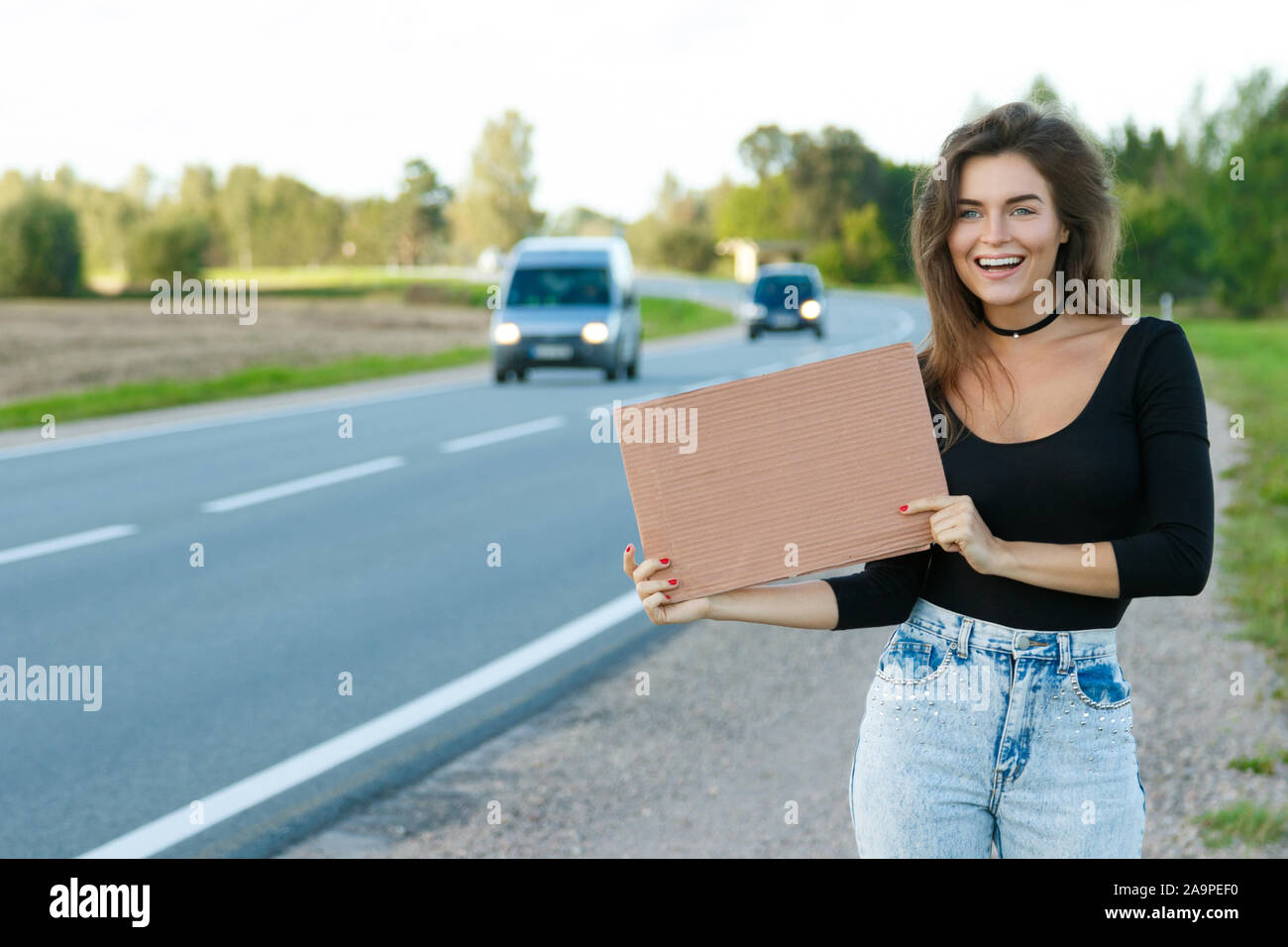 Young woman hitchhiker on the road is holding a blank cardboard sign Stock Photo Alamy