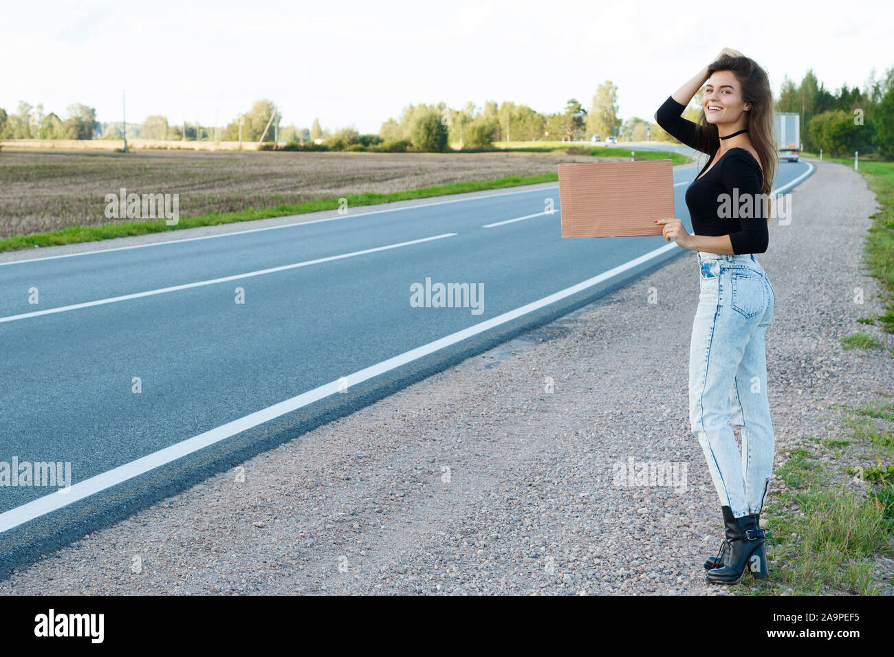 Young woman hitchhiker on the road is holding a blank cardboard sign Stock Photo Alamy