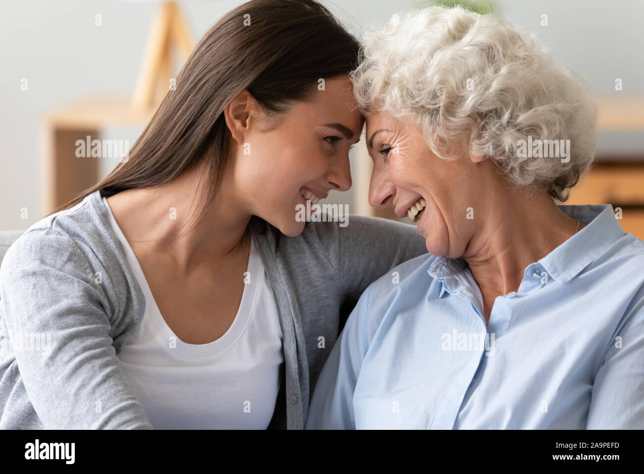 Smiling two generation women family laughing bonding cuddling together Stock Photo