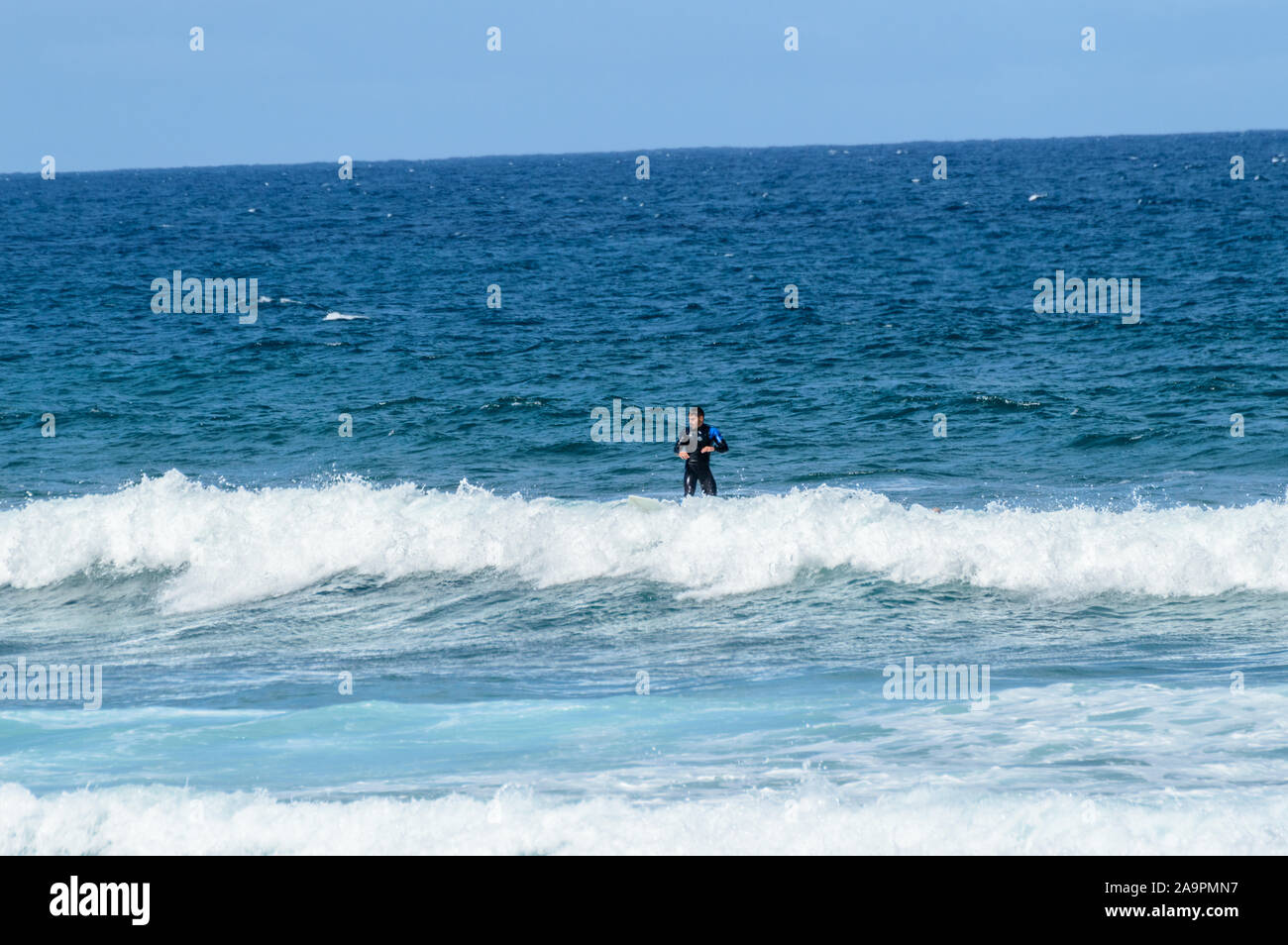 Hispanic Brunette Man Catching Waves On Las Americas Beach. April 11, 2019. Santa Cruz De Tenerife Spain Africa. Travel Tourism Street Photography. Stock Photo