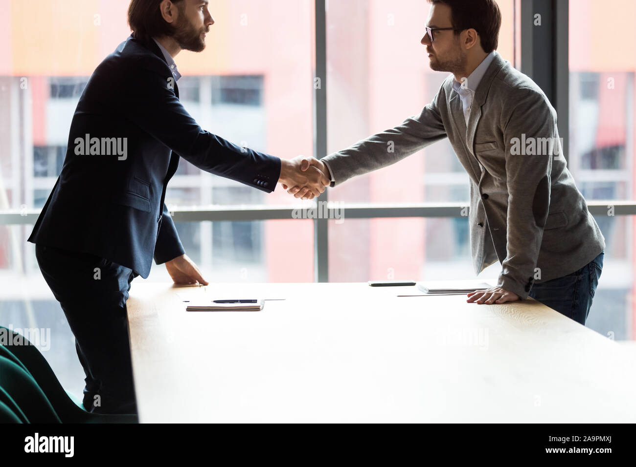 Confident serious two businessmen shaking hands at office. Stock Photo