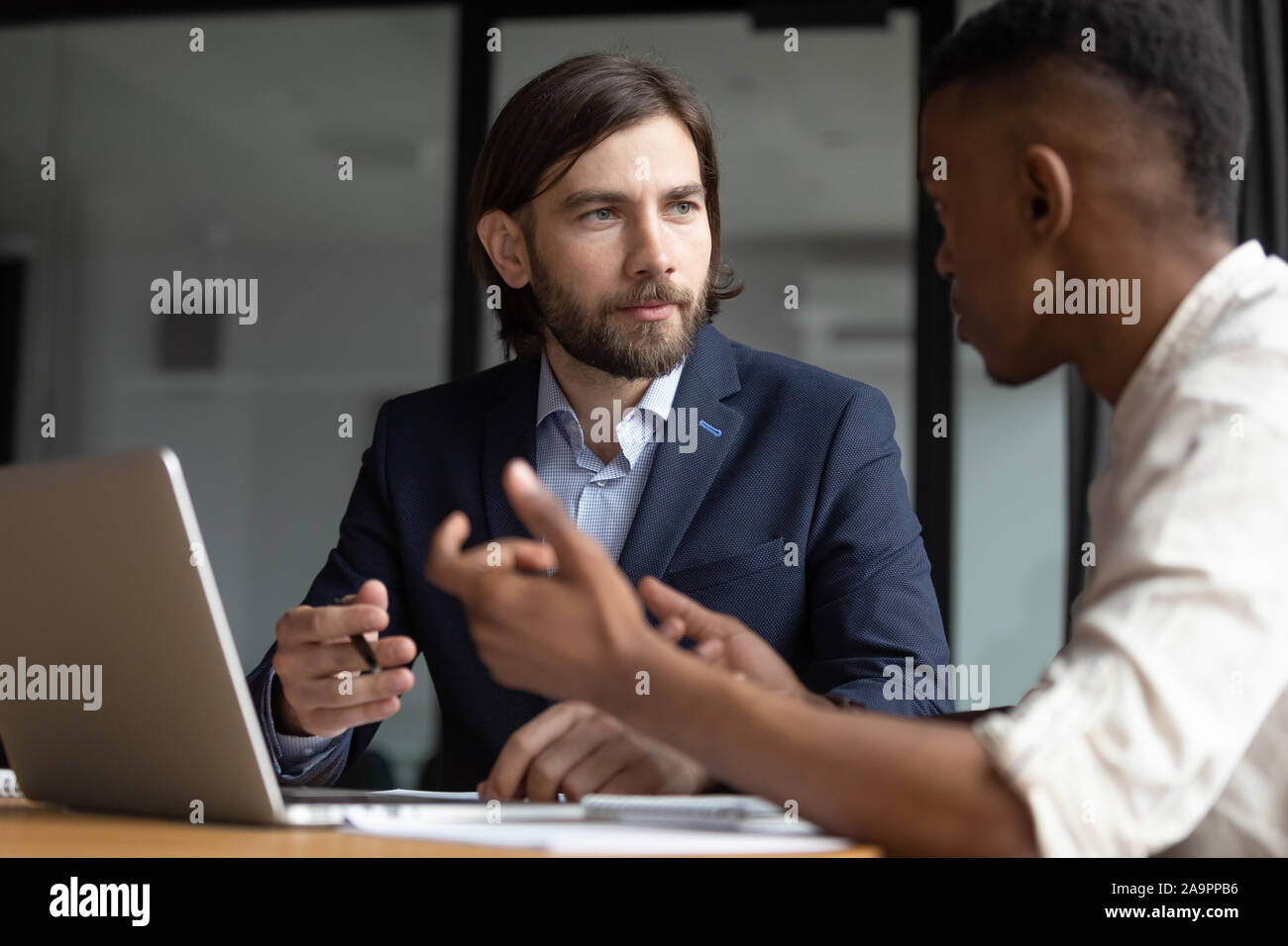 Focused businessman listening to young african american employee. Stock Photo