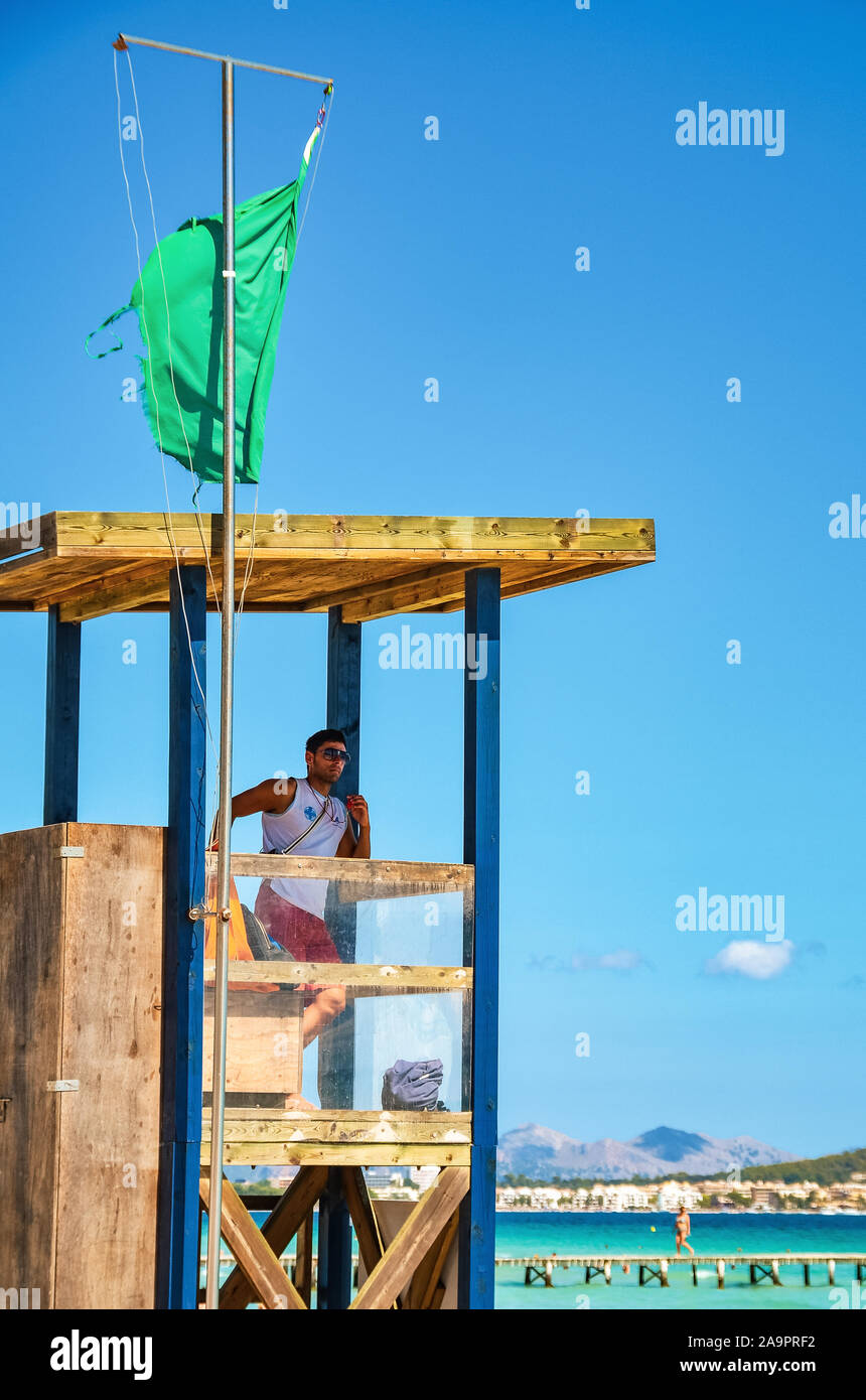 Alcudia, Spain 14.09.2011 - Lifeguard in booth observing people swimming at Playa de Muro beach. Mallorca island famous tourist destination. Stock Photo