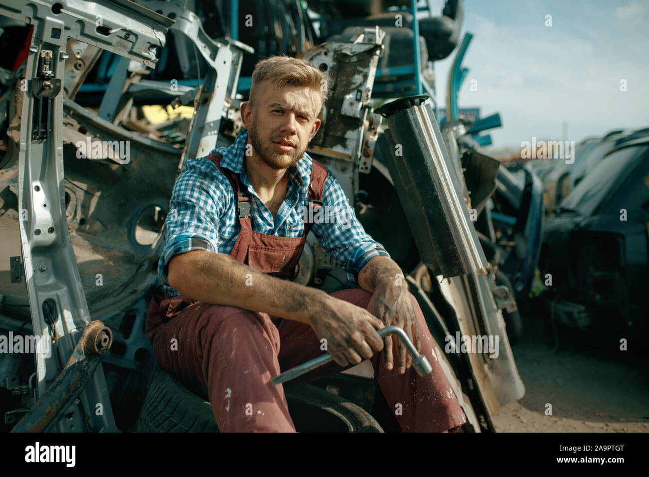 Dirty male repairman with wrench on car junkyard Stock Photo Alamy