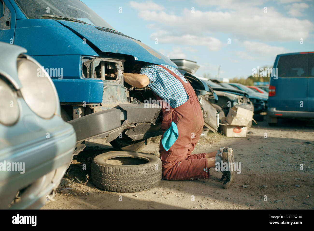 Mechanic stuck head under the hood, car junkyard Stock Photo Alamy