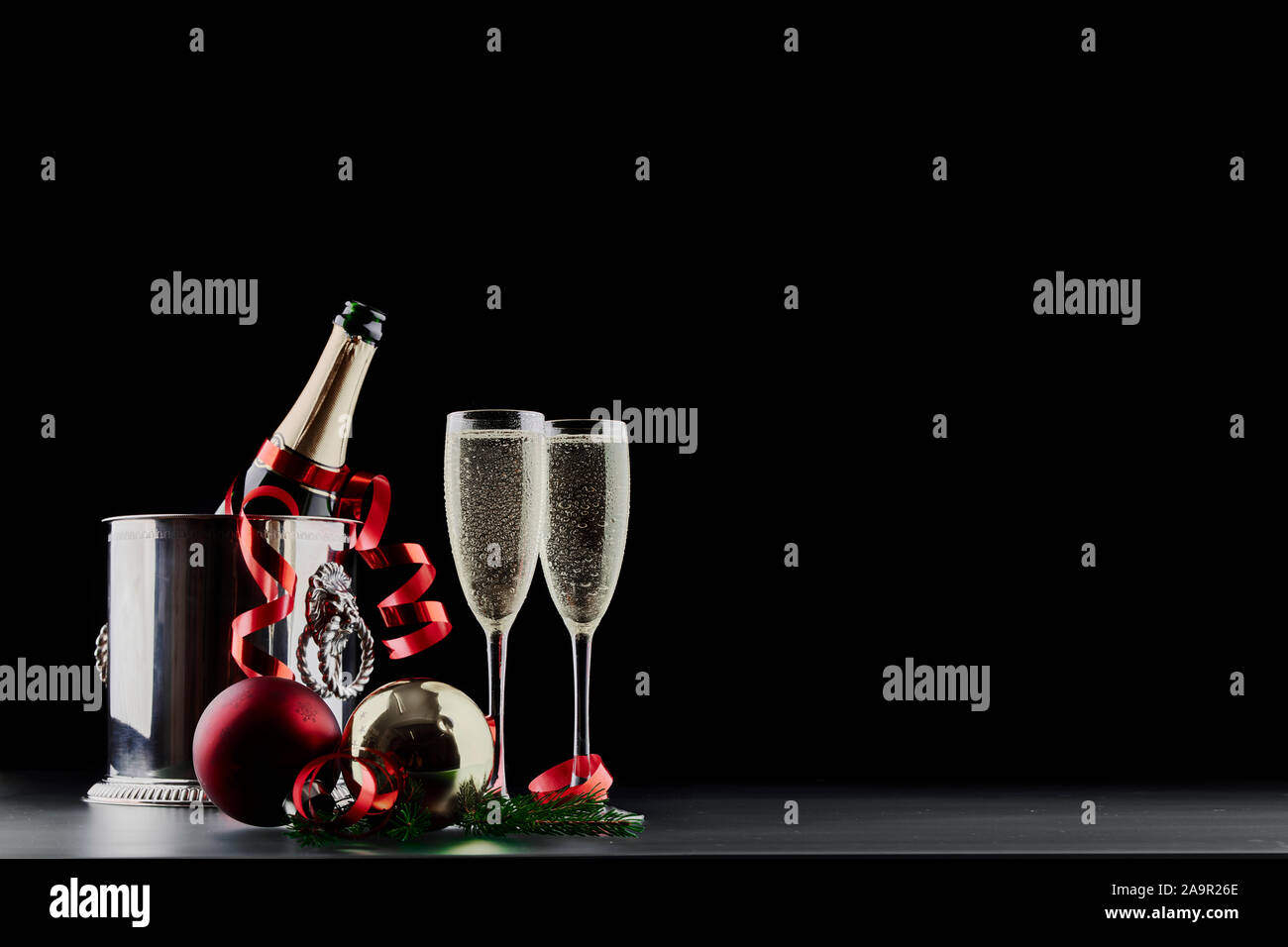 Christmas and New Years Eve celebration concept: two glasses with fizzy drink and a bottle of champagne in ice bucket with festive decorations Stock Photo