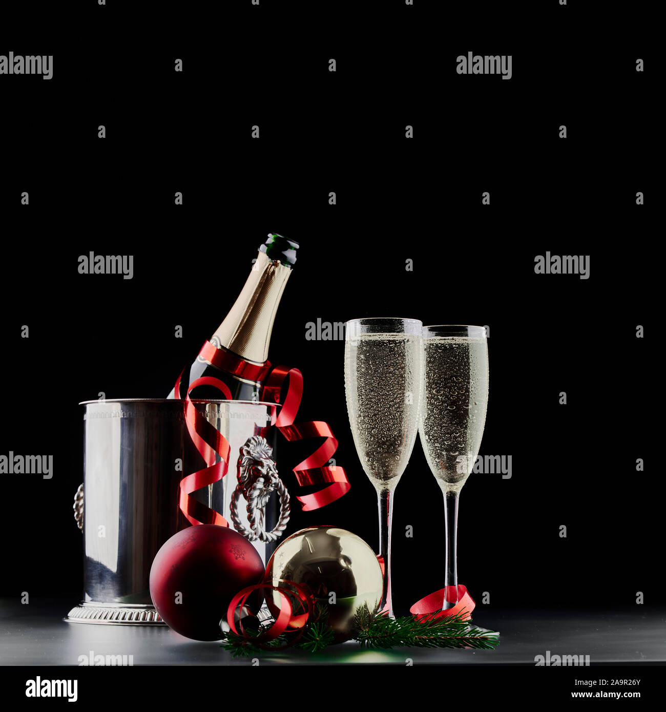 Christmas and New Years Eve celebration concept: two glasses with fizzy drink and a bottle of champagne in ice bucket with festive decorations Stock Photo