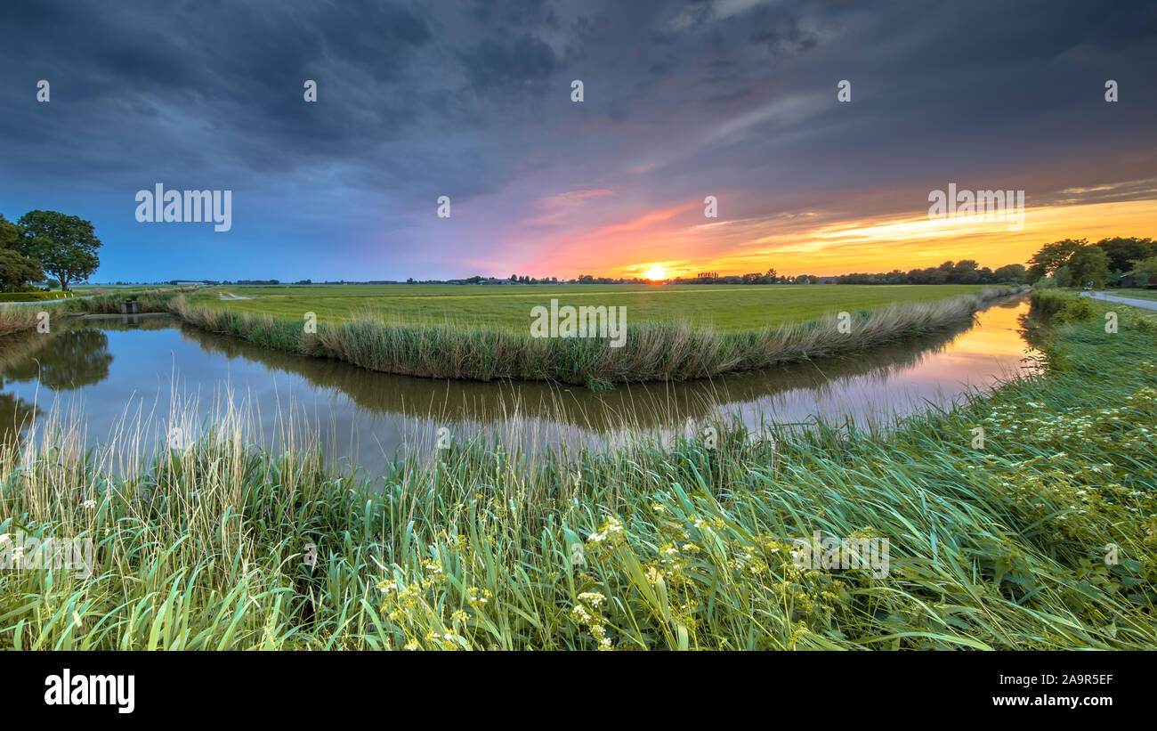 Wide angle view of landscape over river bend at sunset in flat agricultural landscape in Groningen province the Netherlands Stock Photo