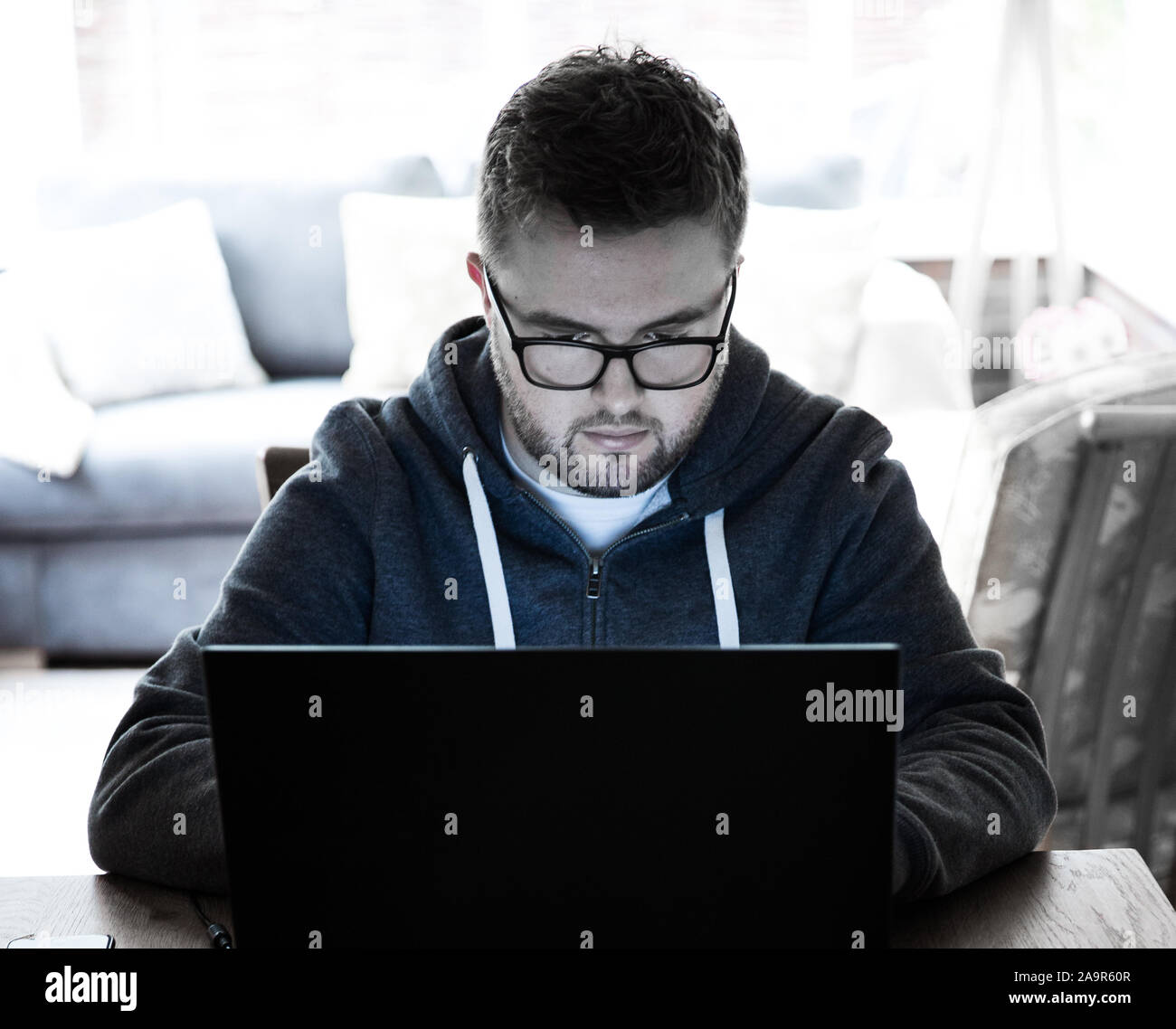 A young man working from home on a laptop computer during the Coronavirus outbreak with copy space Stock Photo