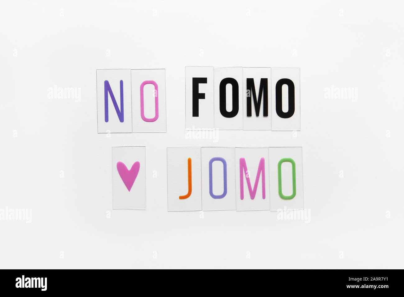 Abbreviation words FOMO, JOMO on transparent plastic on white background. FOMO means Fear Of Missing Out. JOMO - Joy Of Missing Out. Opposition, choic Stock Photo