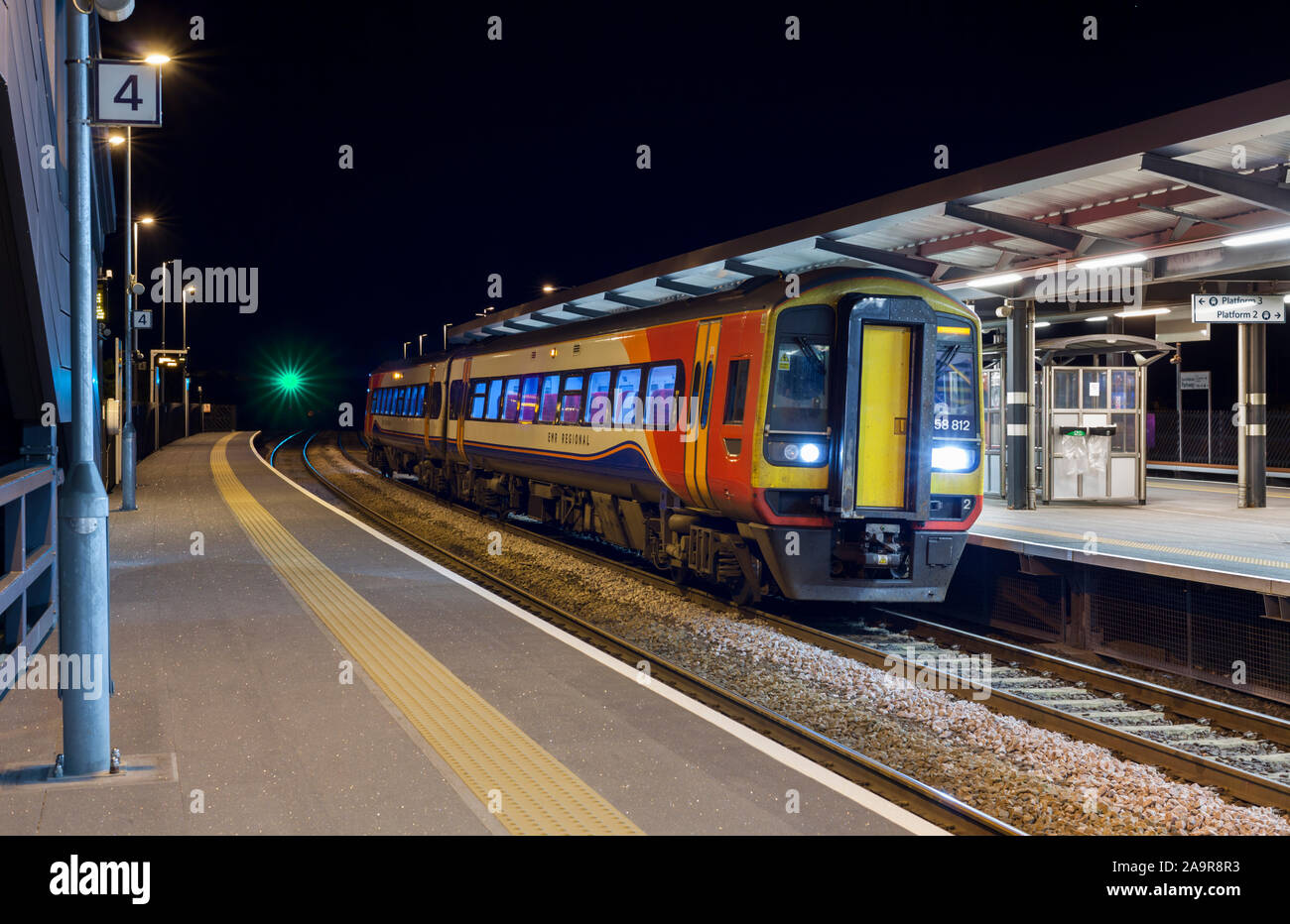 East Midlands railway class 158 sprinter train calling at East Midlands Parkway station  (Ratcliffe On Soar) on a dark night. Stock Photo