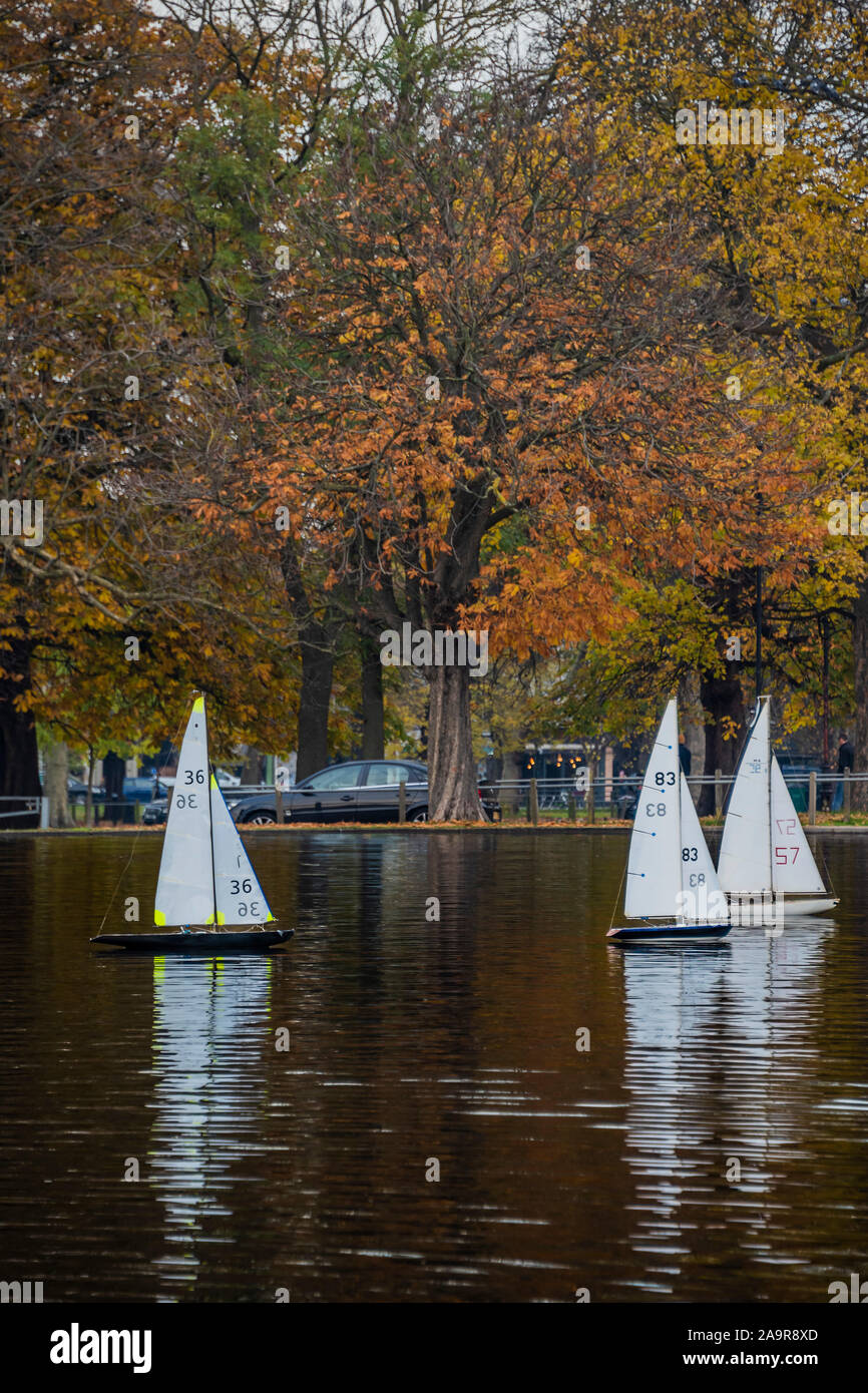 London, UK. 17th Nov 2019. Remote control yachts make slow progress in the light breeze - Autumn trees reflect in the boating lake on Clapham Common, London. Credit: Guy Bell/Alamy Live News Stock Photo