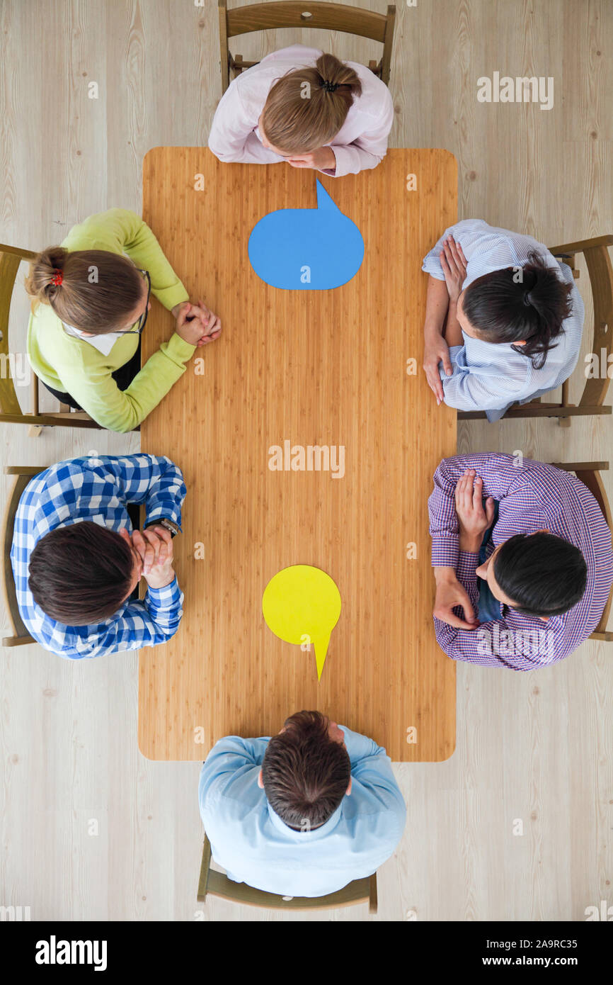 Team of business people in casual clothes sitting around the table with