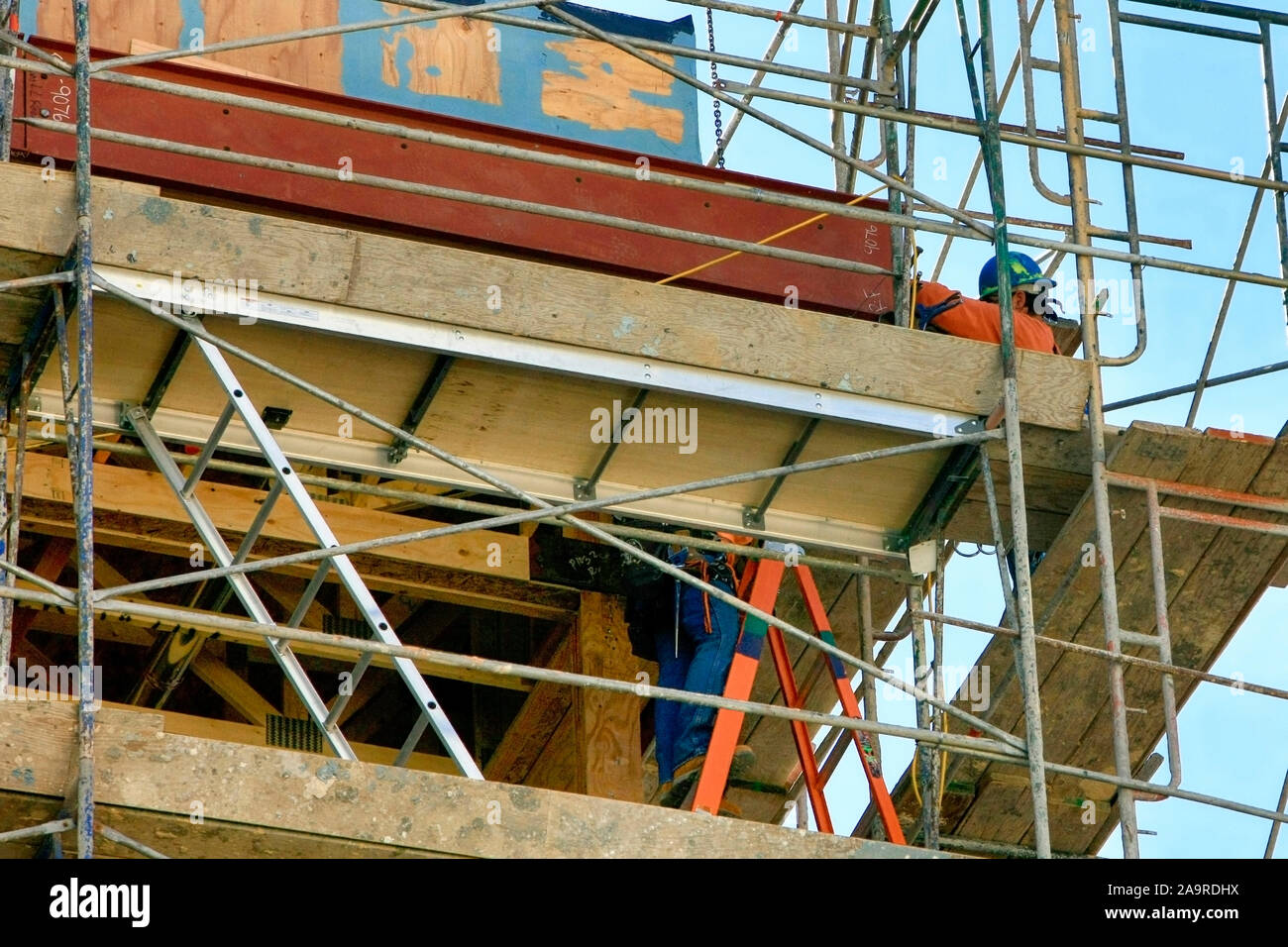 Two construction workers wearing safety equipment go about their jobs