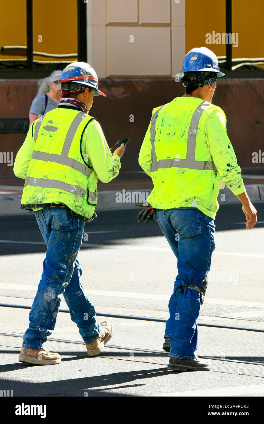 Two construction workers wearing their hardhats and high viz vests