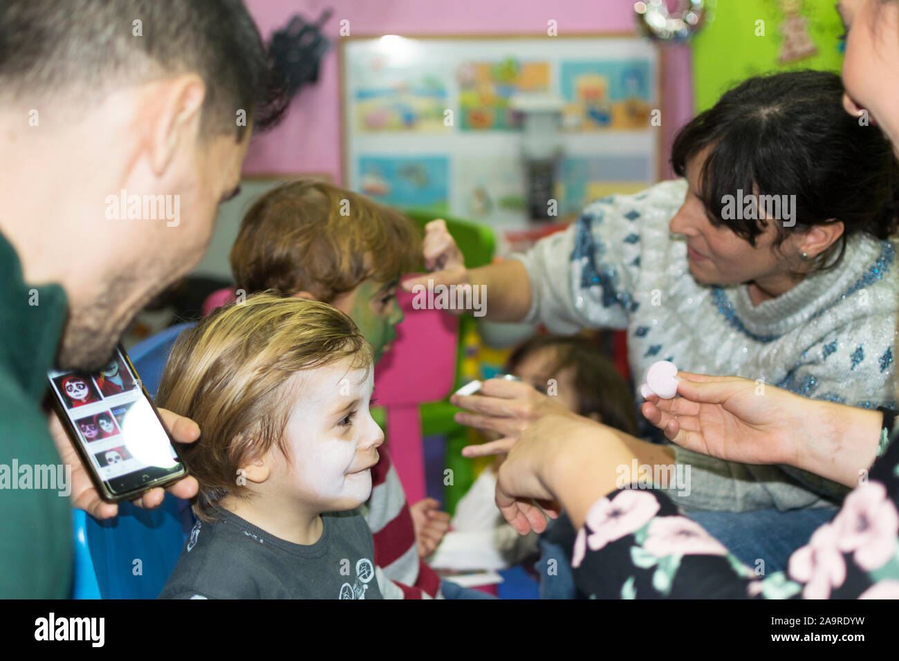 Face painting to a little girl at a birthday party. Mother paints her child's face with paint. Stock Photo