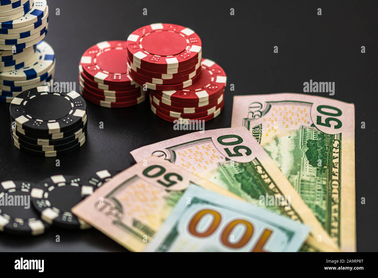 Stacks of poker chips and dollar bills on black background. Poker