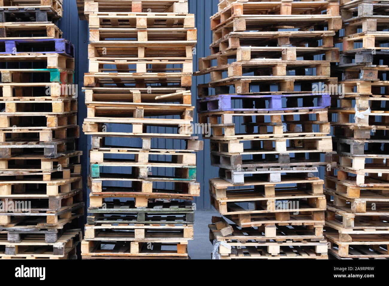Stacks of colorful rough wooden pallets at warehouse in industrial yard. Pallets background. Cargo and shipping concept. Stock Photo