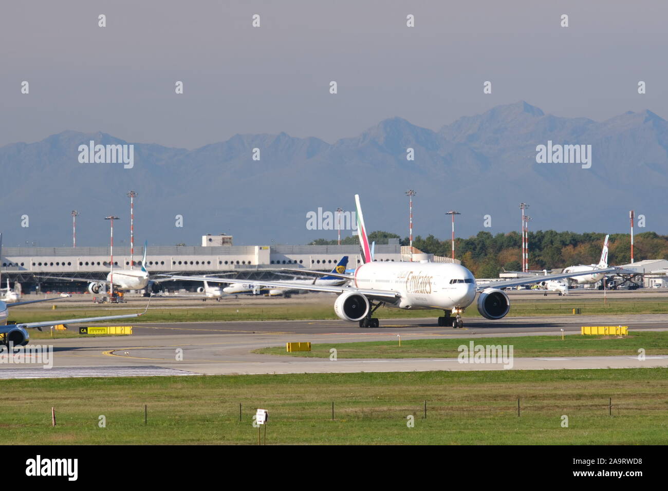 Milano, Malpensa, Lombardy, Italy. About 10/2019.  Emirates Boeing 777-31H  airplane on the Malpensa airport runway. In the background the terminal 1 Stock Photo