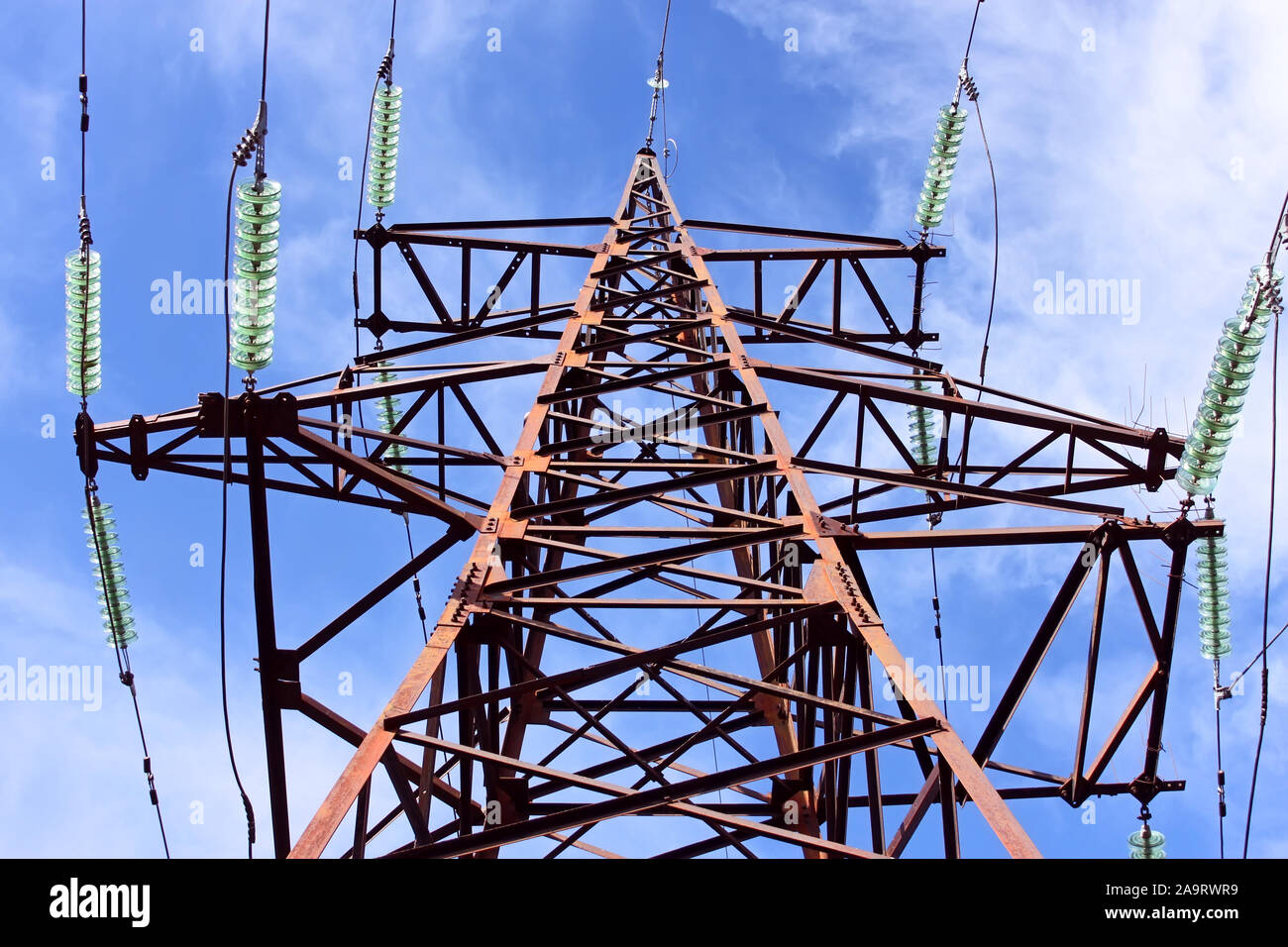 High-voltage electric lattice tower with wires and insulators against the sky Stock Photo
