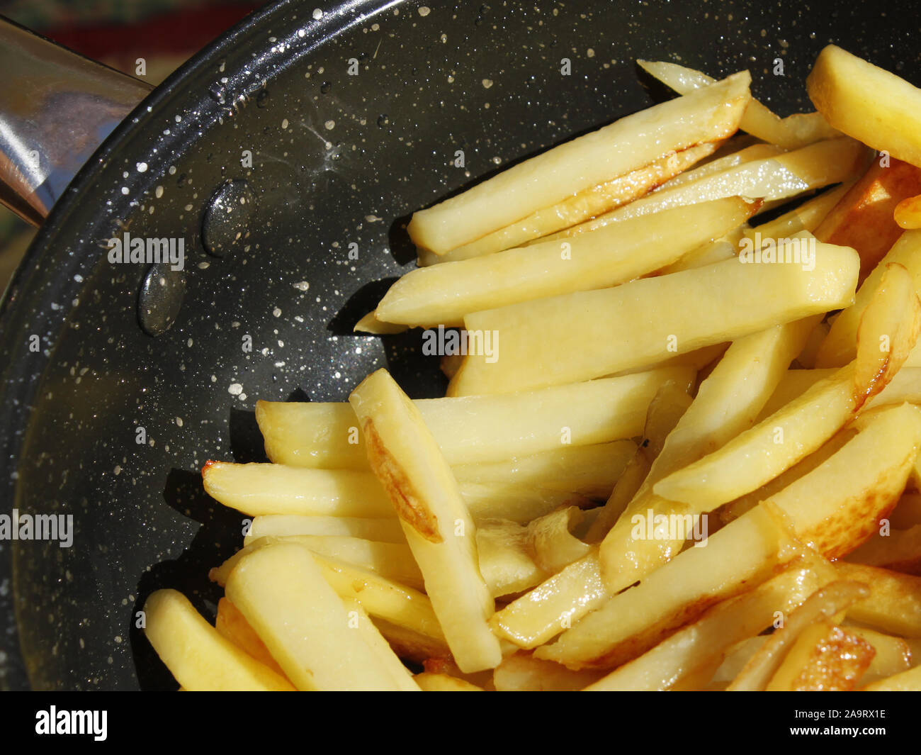 Fresh appetizing roasted potato chips in a frying pan close-up, in bright sunlight Stock Photo