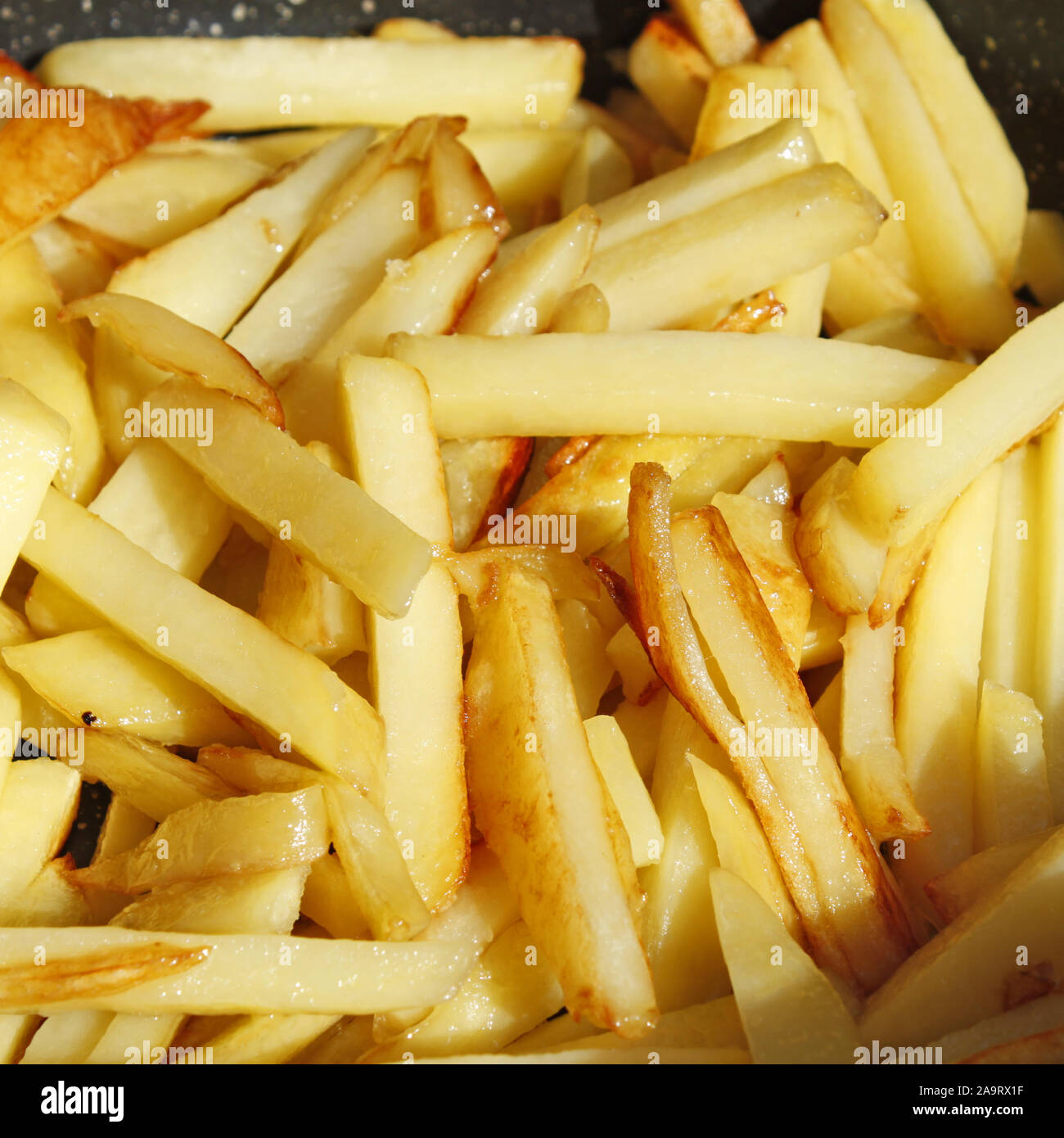 Heap of appetizing roasted potato chips close-up, in bright sunlight Stock Photo