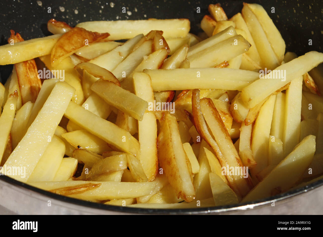 Roasted potato chips in a frying pan close-up, in bright sunlight Stock Photo