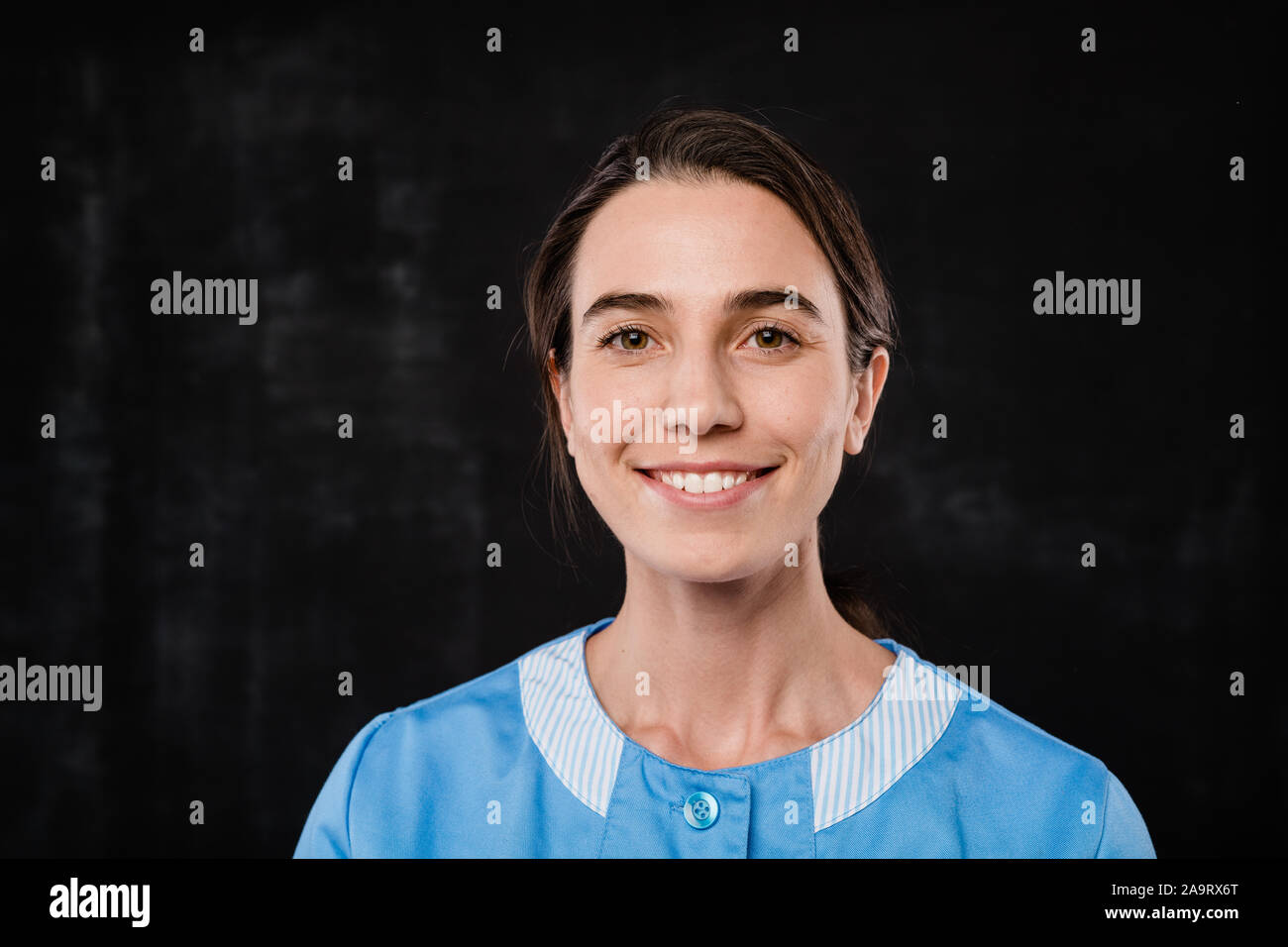 Pretty young hotel room service staff in uniform standing in front of camera Stock Photo