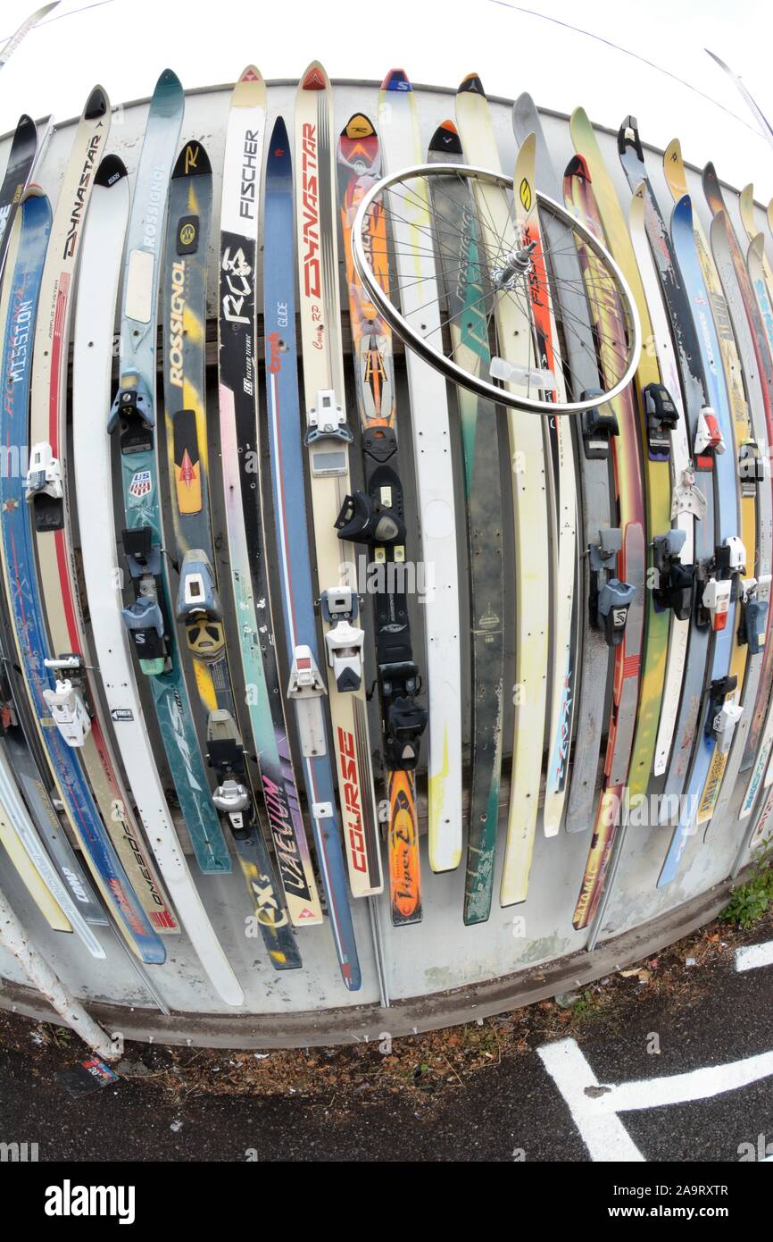 Skis used to cover fence in parking lot as art behind a handicapped parking space in Bend Oregon USA Stock Photo