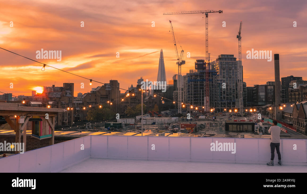 Tobacco Dock, London, UK, 17th November 2019. Skating at sunset. People enjoy spectacular views across to the City of London at London's trendy Skylight ice rink, a rooftop at the historic Tobacco Dock complex in Wapping, East London. Credit: Imageplotter/Alamy Live News Stock Photo