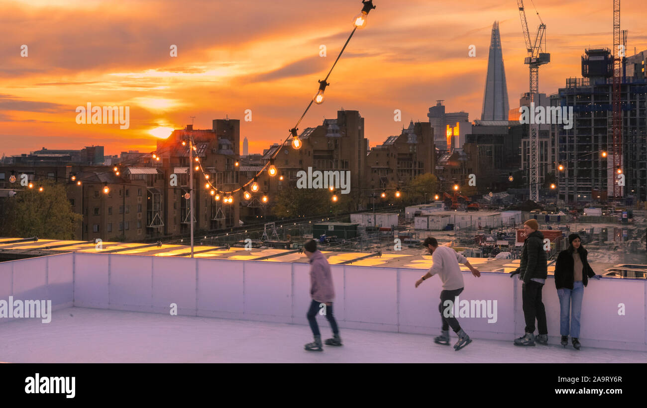 Tobacco Dock, London, UK, 17th November 2019. Skating at sunset. People enjoy spectacular views across to the City of London at London's trendy Skylight ice rink, a rooftop at the historic Tobacco Dock complex in Wapping, East London. Credit: Imageplotter/Alamy Live News Stock Photo