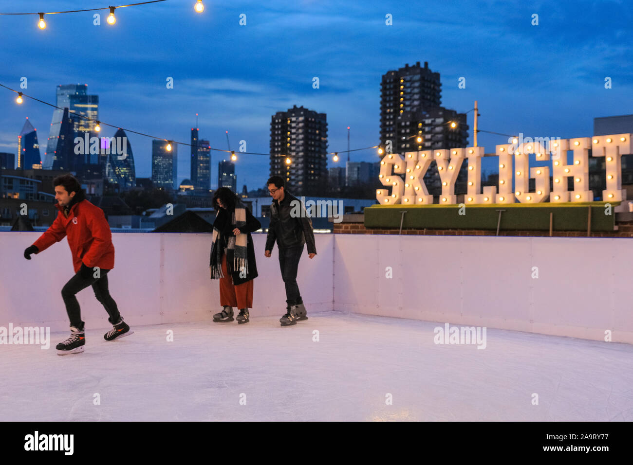 Tobacco Dock, London, UK, 17th November 2019. People enjoy spectacular views across to the City of London at London's trendy Skylight ice rink, a rooftop at the historic Tobacco Dock complex in Wapping, East London. Credit: Imageplotter/Alamy Live News Stock Photo