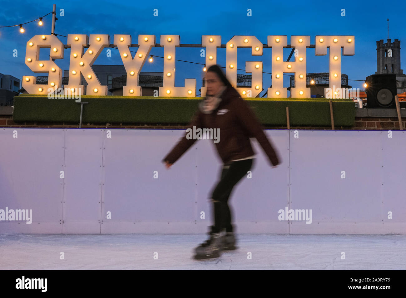 Tobacco Dock, London, UK, 17th November 2019. People enjoy spectacular views across to the City of London at London's trendy Skylight ice rink, a rooftop at the historic Tobacco Dock complex in Wapping, East London. Credit: Imageplotter/Alamy Live News Stock Photo