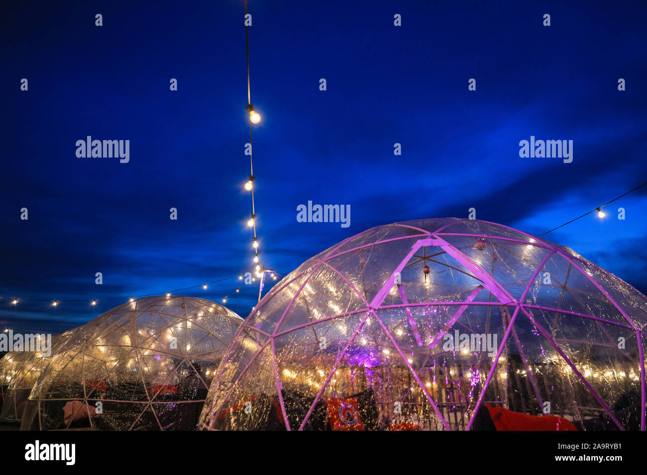 Tobacco Dock, London, UK, 17th November 2019. Igloo pods keep those watching and enjoying a drink warm. People enjoy spectacular views across to the City of London at London's trendy Skylight ice rink, a rooftop at the historic Tobacco Dock complex in Wapping, East London. Credit: Imageplotter/Alamy Live News Stock Photo
