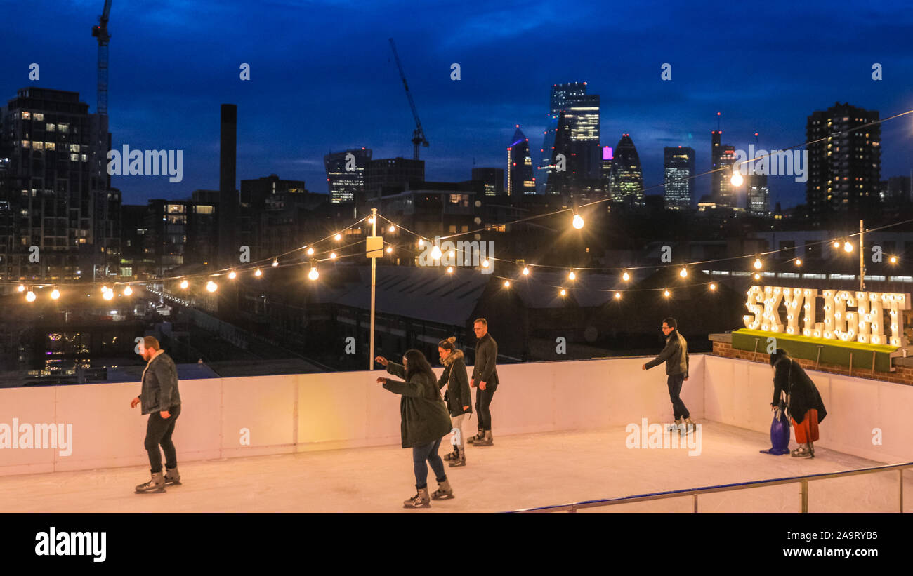 Tobacco Dock, London, UK, 17th November 2019. People enjoy spectacular views across to the City of London at London's trendy Skylight ice rink, a rooftop at the historic Tobacco Dock complex in Wapping, East London. Credit: Imageplotter/Alamy Live News Stock Photo