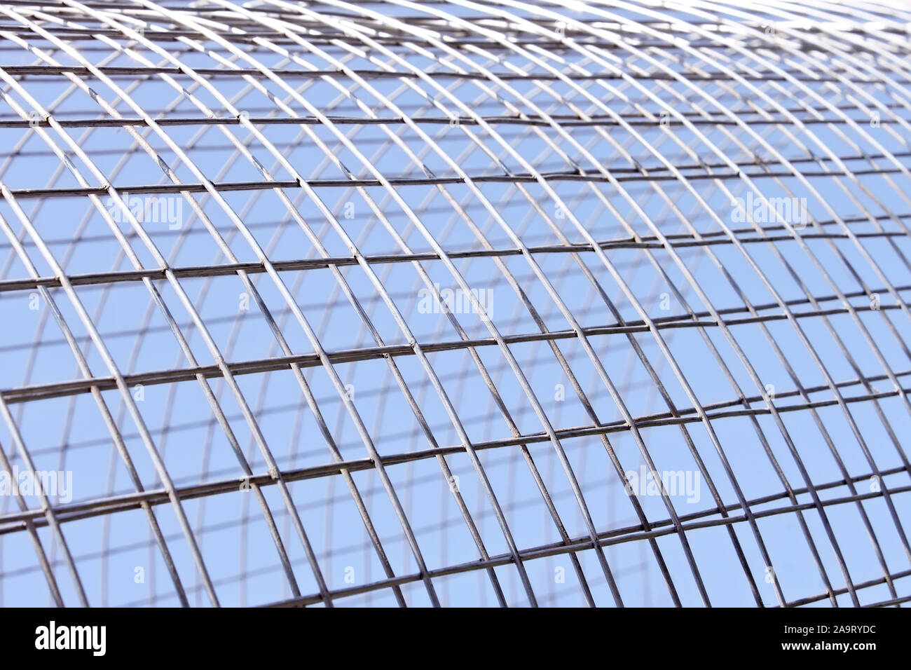 Metal grid of white alloy shines in bright sunlight on the blue sky background Stock Photo