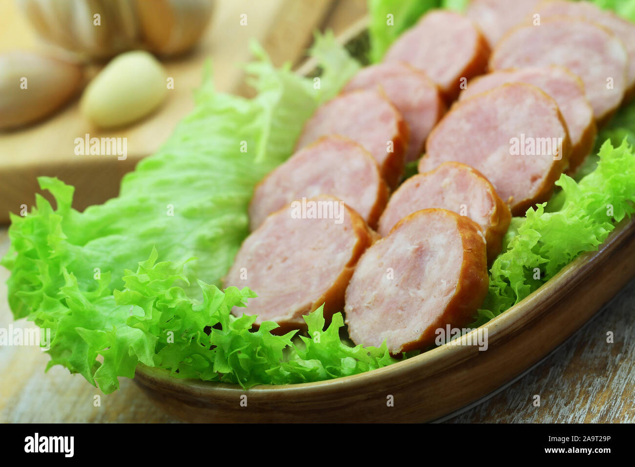 Slices of traditional Polish pork sausage on lettuce, closeup Stock Photo