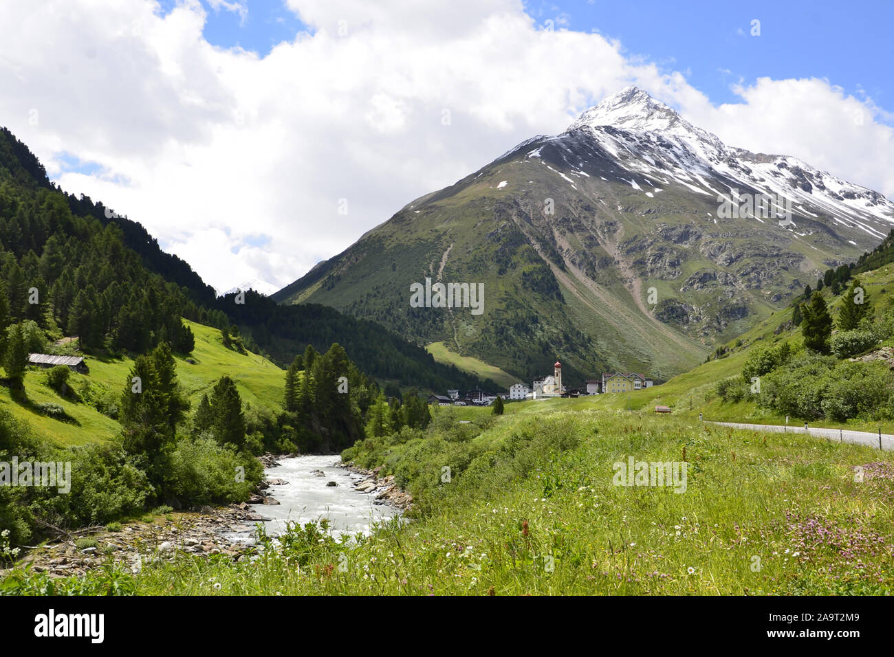 Tyrolean village with snow capped mountains, pine trees and alpine river in Austria Stock Photo