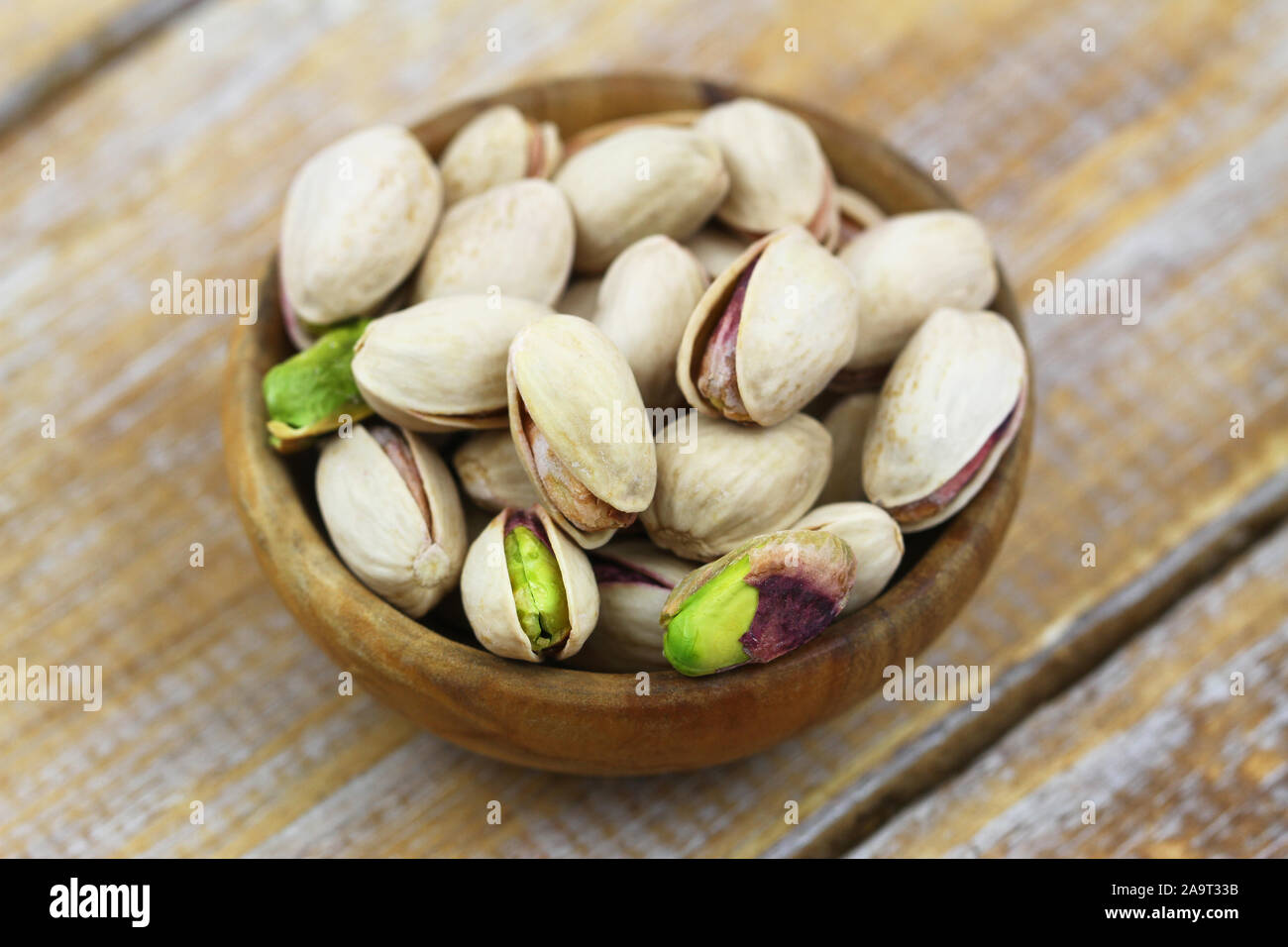 Closeup of delicious pistachio nuts in small wooden bowl Stock Photo