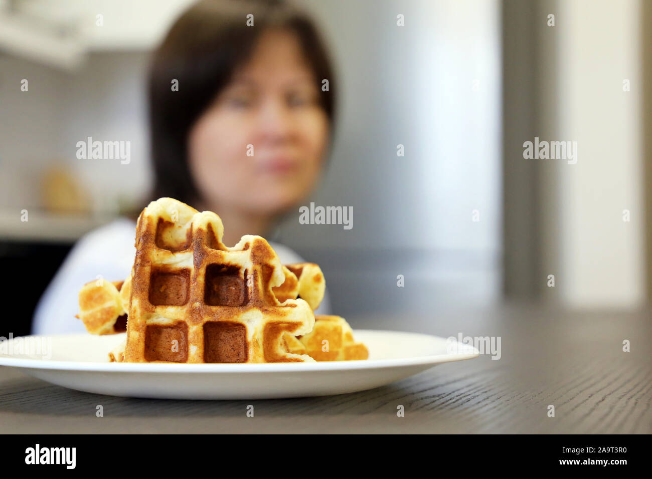 Diet and gluttony, woman looking on belgian waffles in a plate, selective focus. Tasty breakfast close up, delicious food, sweet tooth Stock Photo