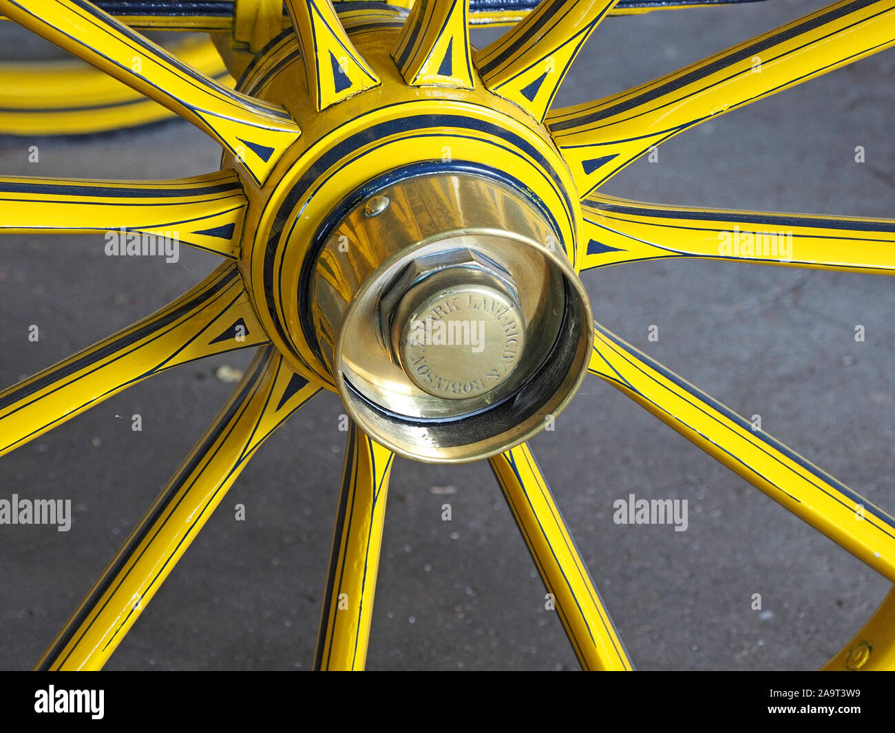 bright yellow & black spokes and axle with brass hub of wooden wheel of historic carriage in a collection in England, UK Stock Photo