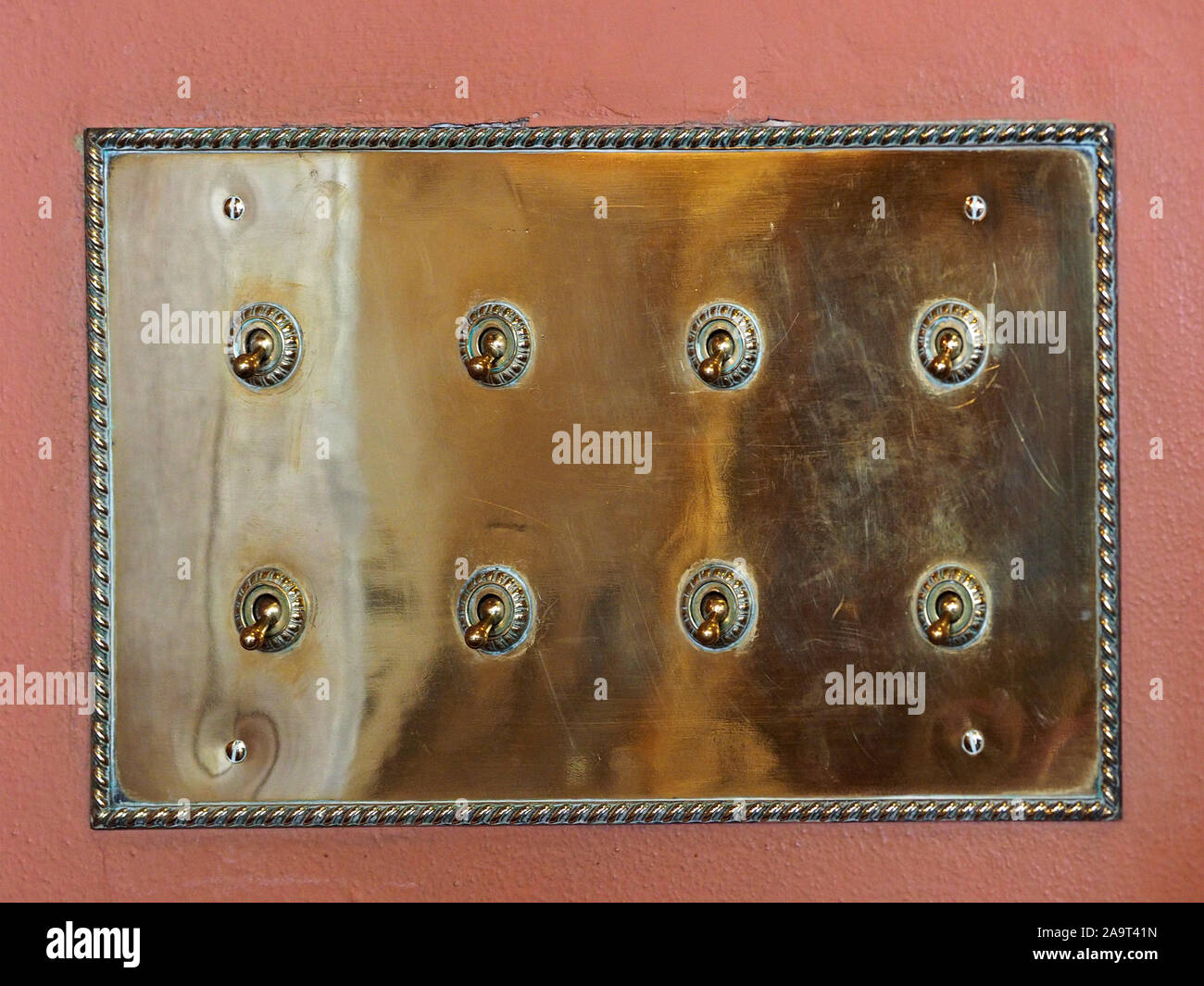 shiny brass switchplate with eight old fashioned electrical switches