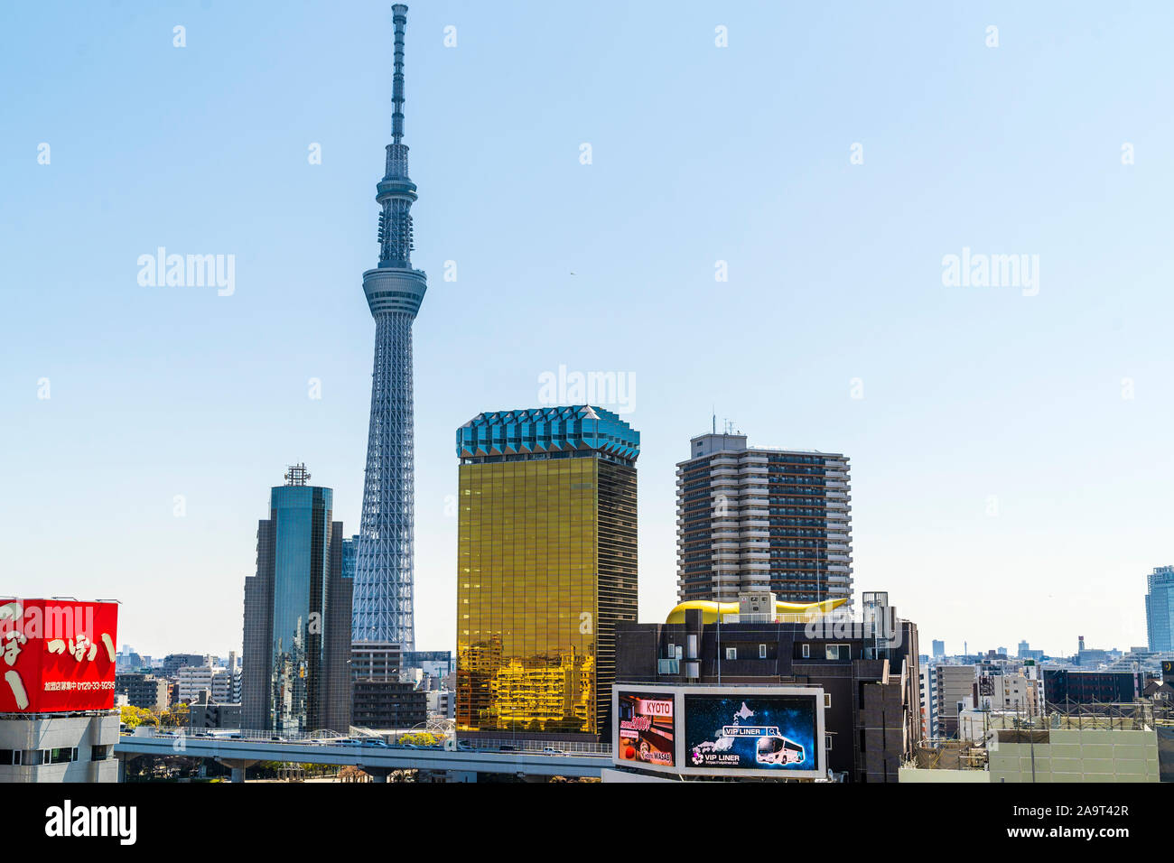 Distant shot of the Skytree tower viewed from Asakusa in Tokyo with the Asahi Beer headquaters, and Sumida Ward Office in the foreground. Blue sky. Stock Photo