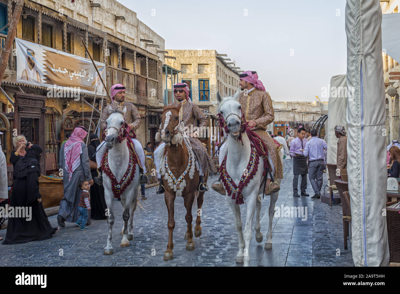 Doha-Qatar, January 24,2013: Souk Waqif in Doha Qatar main street day light view with traditional guards riding horses and people walking Stock Photo