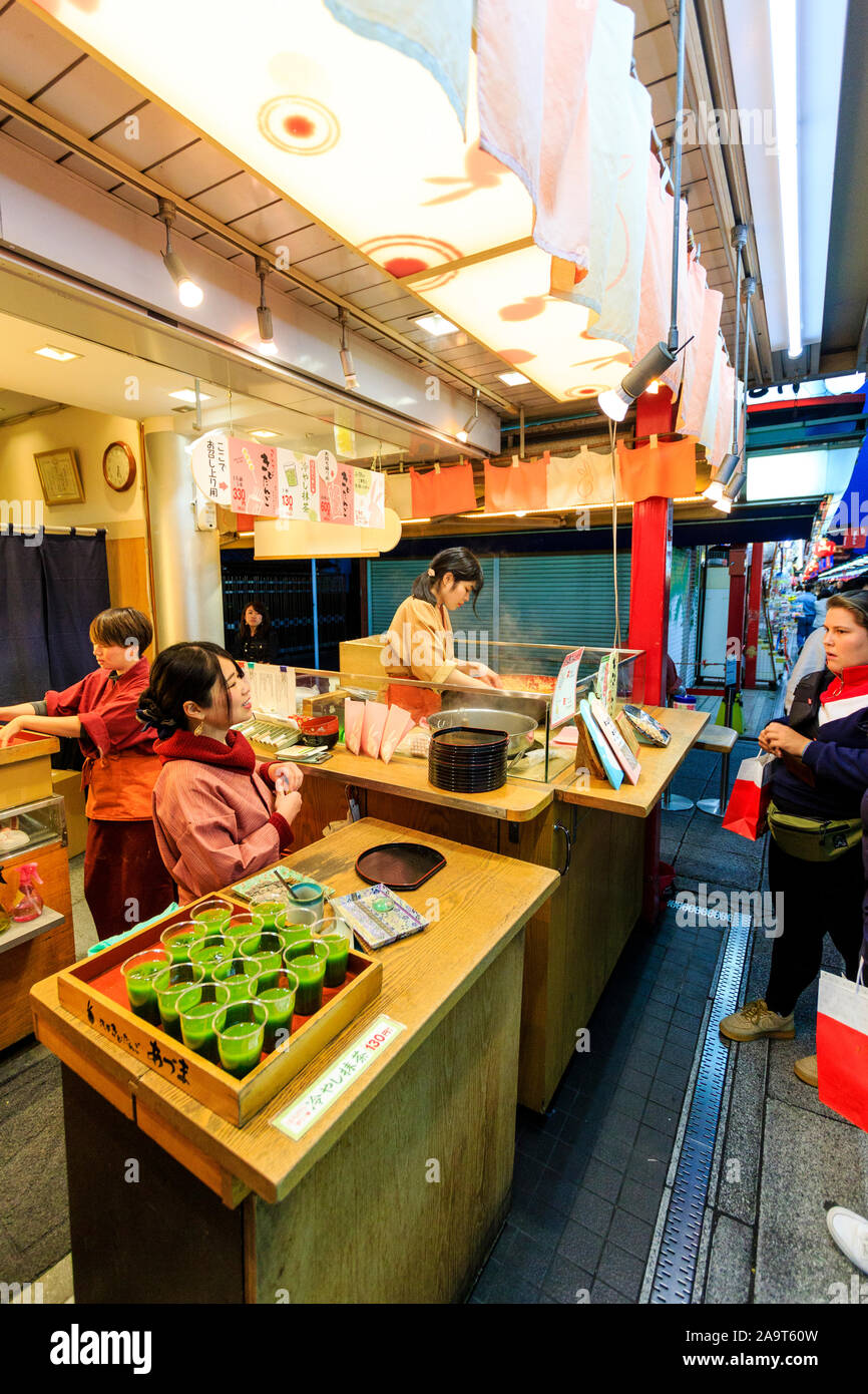 Tokyo, The popular Asakusa shrine and Sensoji temple. Caucasian woman buying green drink from food and drink shop on Nakamise dori, street. Night time Stock Photo