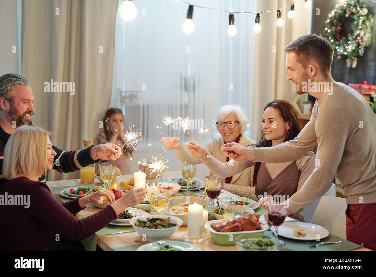 Young and mature adults holding sparkling bengal lights over served table Stock Photo