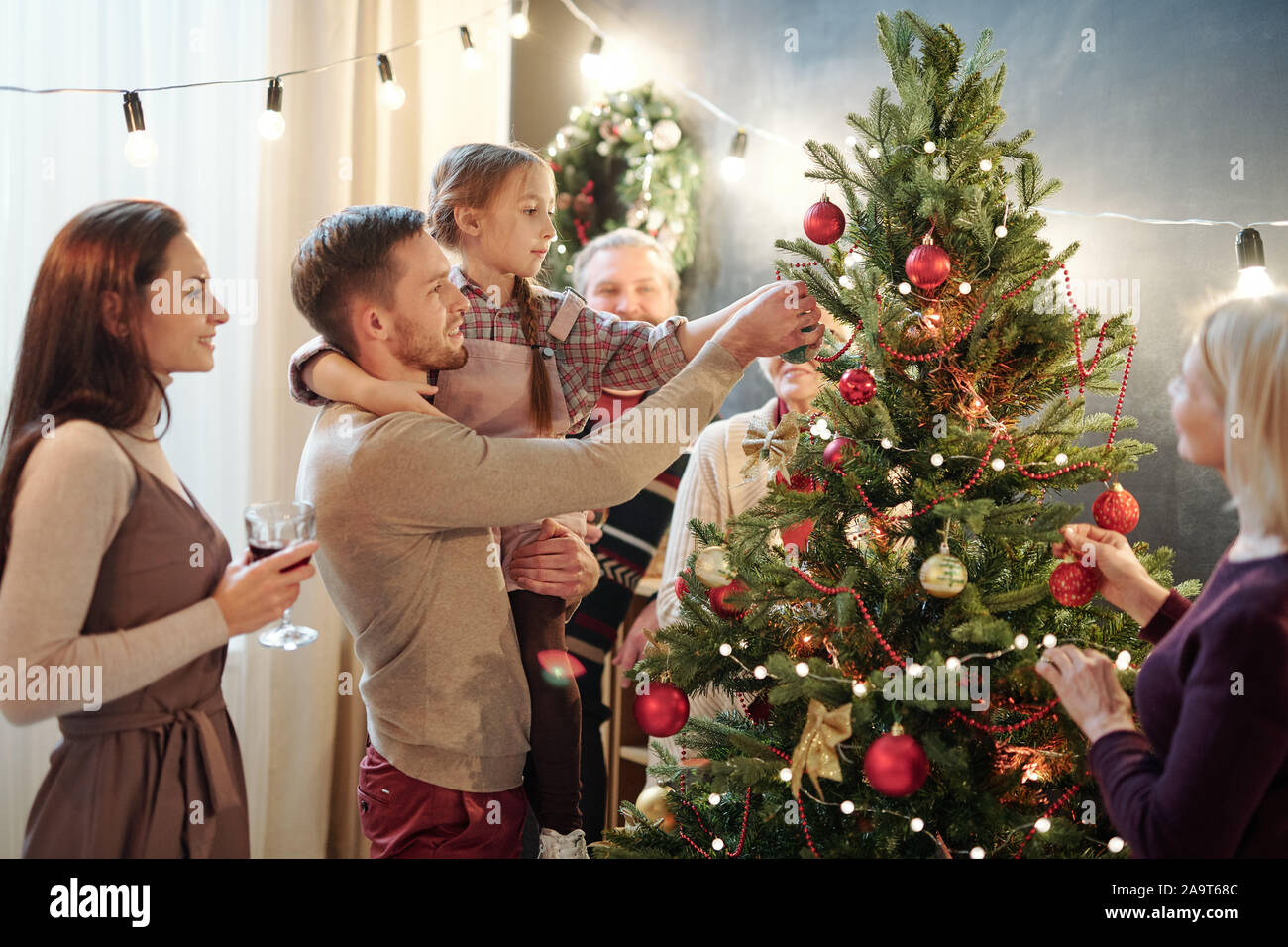 Young man with his little daughter decorating Christmas tree at home Stock Photo