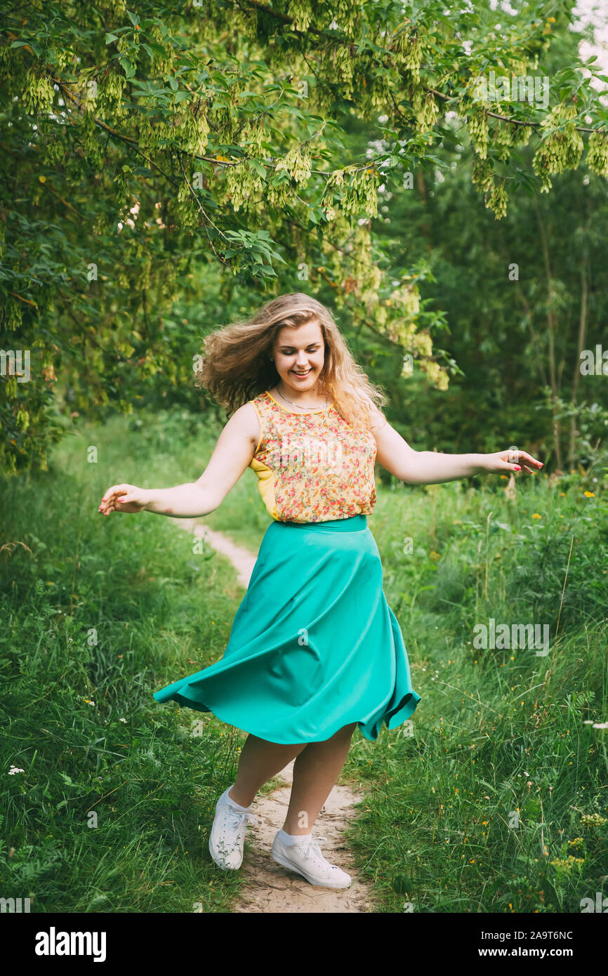 Single Young Pretty Plus Size Caucasian Happy Smiling Girl Woman Dancing In Summer Green Forest. Fun Enjoy Outdoor Summer Nature. Stock Photo